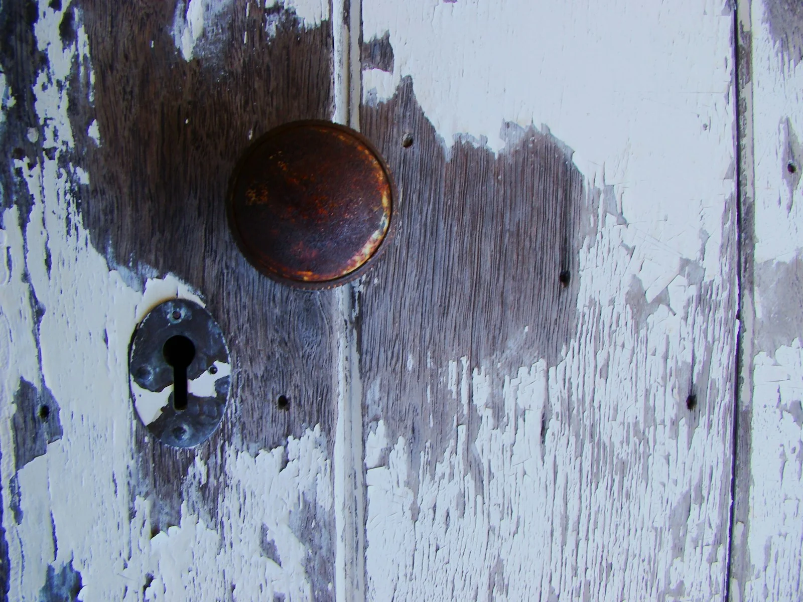 Old, peeling door with doorknob and keyhole